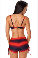 Back view of a woman wearing a red and black gradient stripe bikini