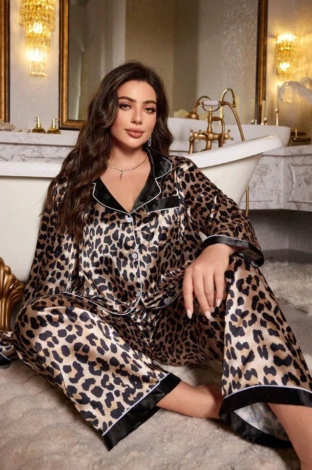Woman wearing a leopard print satin pajama set, sitting on a rug in front of a bathtub.