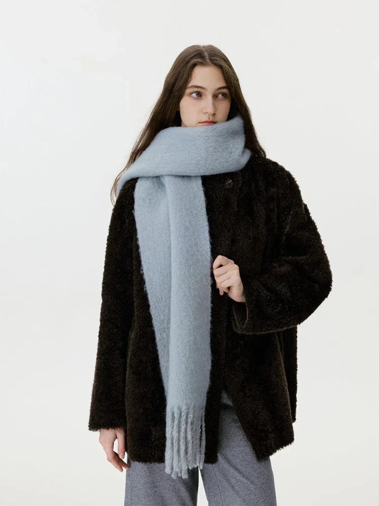 Model in a dark brown fuzzy coat and a light blue scarf, looking to the side.