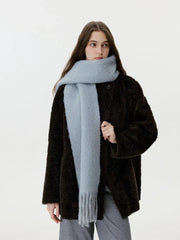 Model in a dark brown fuzzy coat and a light blue scarf, looking to the side.