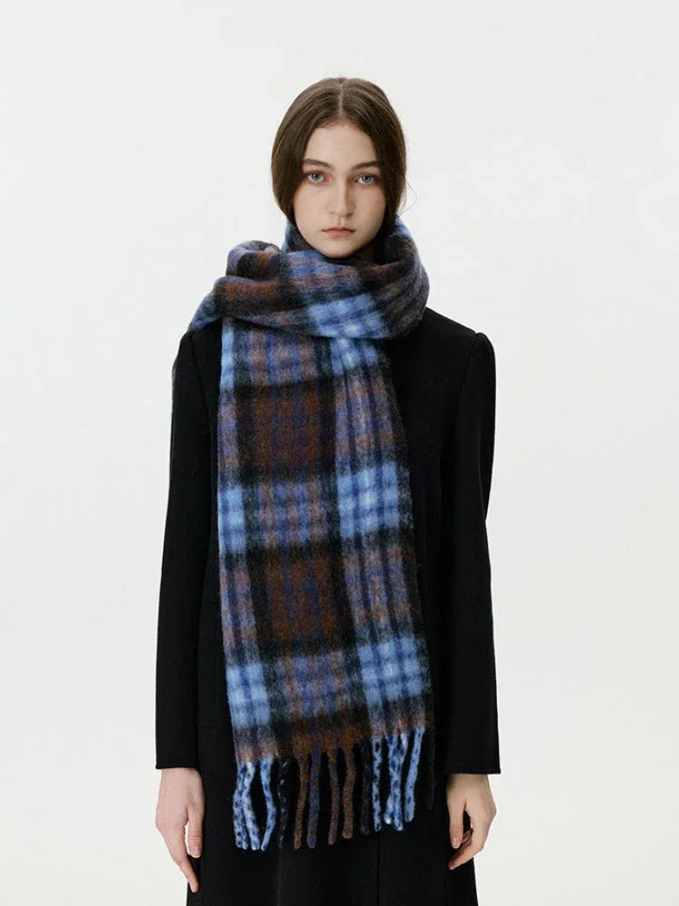 Front view of a woman wearing a black coat and a blue and brown plaid scarf with fringe.