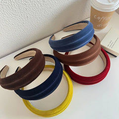 Collection of velvet padded headbands in various colors arranged on a white surface