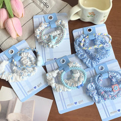 Collection of scrunchie sets with various blue and white patterns and charms