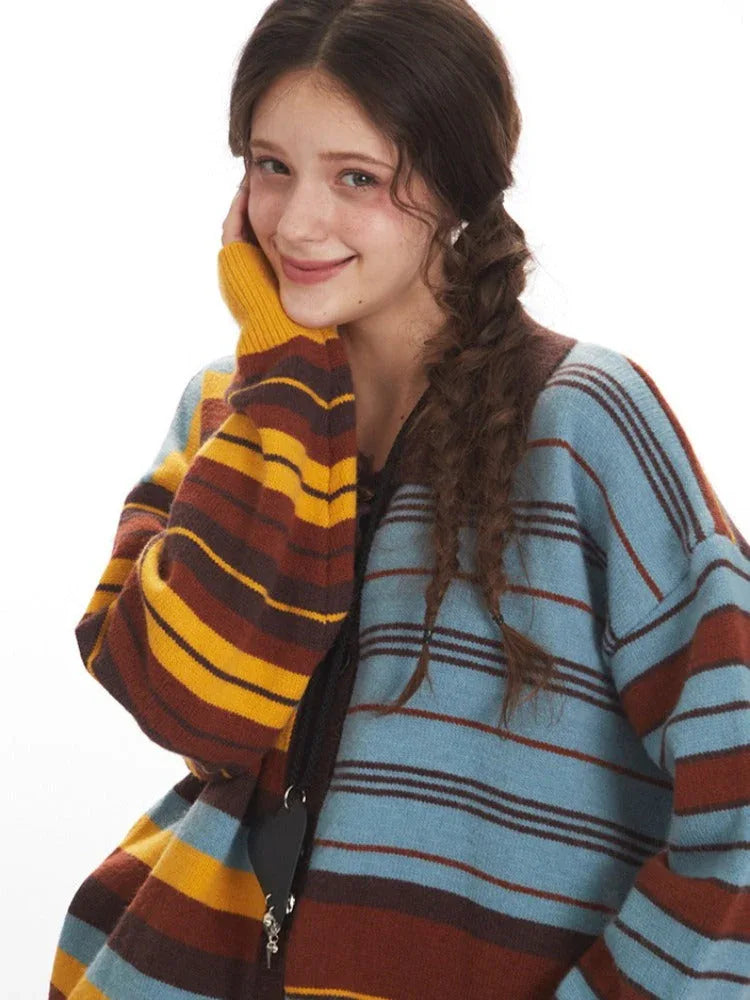 Close-up of a woman wearing a striped knit cardigan, touching her face and smiling.