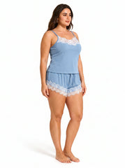 Back view of a woman in a blue camisole and shorts pajama set, highlighting the spaghetti straps and lace trim on the shorts.
