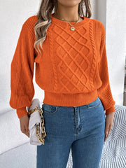 Front view of a woman in an orange cable knit sweater and blue jeans, holding a white handbag