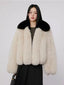 Woman wearing a cream faux fur cropped jacket with a black collar and a black dress.