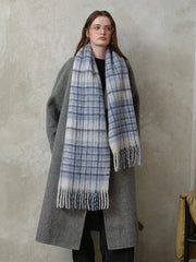 Woman wearing a grey coat and a blue and white plaid scarf.