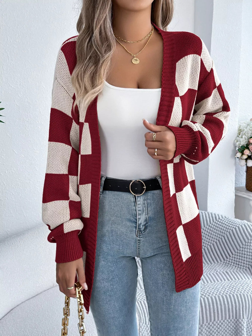 Close-up of a woman wearing a red and cream checkerboard knit cardigan, showing the neckline and jewelry.