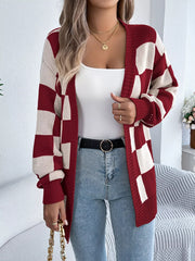 Close-up of a woman wearing a red and cream checkerboard knit cardigan, showing the neckline and jewelry.
