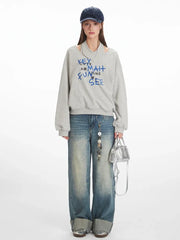 Model wearing a grey graphic print sweatshirt and wide-leg jeans, front view