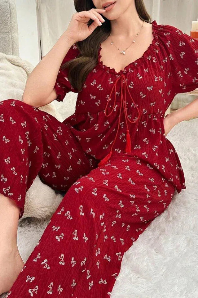 Woman wearing a red pajama set with a butterfly print, sitting.