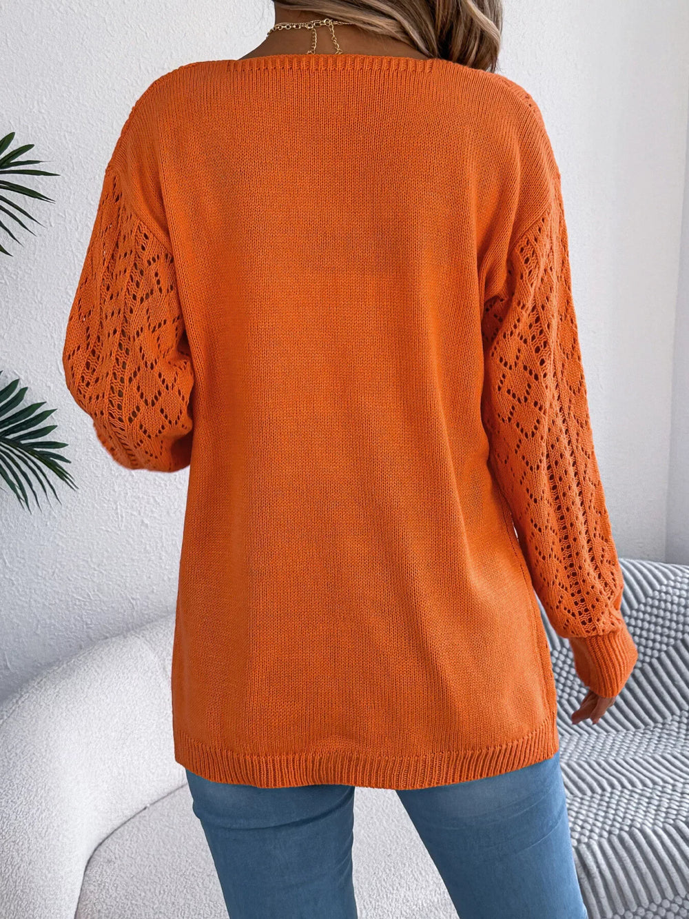 Back view of a woman wearing an orange open-front knit cardigan.