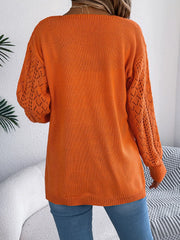 Back view of a woman wearing an orange open-front knit cardigan.