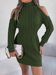 woman holding a white clutch and wearing a green knitted cold shoulder mock neck dress