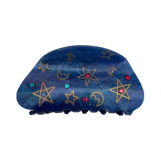 A blue claw hair clip with a celestial pattern of gold stars and moons, accented with colorful gemstones.
