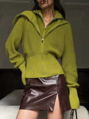 Model wearing a lime green zip-up knit sweater with a brown leather mini skirt.