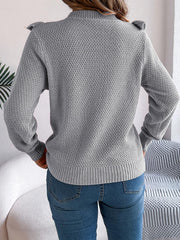 woman wearing a grey knit sweater with ruffle trim and blue jeans from the back
