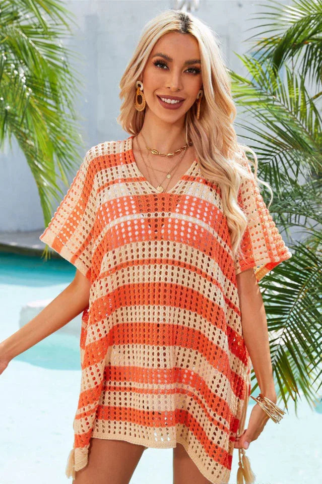 Woman wearing an orange and beige striped crocheted poncho with a V-neck and short sleeves.
