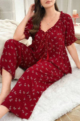 Woman wearing a red pajama set with a butterfly print, sitting on a white rug.