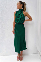 woman wearing a green satin halter neck midi dress indoors
