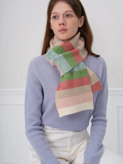 Woman wearing a blue sweater and a pastel striped scarf