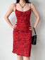 Model wearing a red floral print midi dress with adjustable spaghetti straps and a tie front detail.
