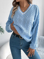 woman wearing a light blue cable knit v-neck sweater with white stripes, blue jeans, and gold necklaces