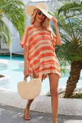 Woman wearing an orange and beige striped crocheted poncho with a V-neck and short sleeves, carrying a straw bag and wearing a straw hat.