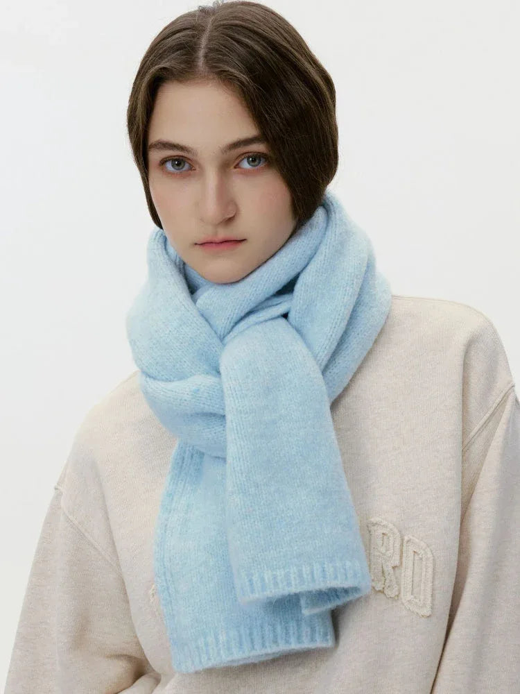 Model wearing a cream sweatshirt and a thick light blue knit scarf wrapped around her neck, front view.