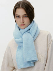Model wearing a cream sweatshirt and a thick light blue knit scarf wrapped around her neck, front view.