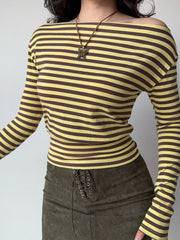 Woman wearing a yellow and brown striped off-the-shoulder long-sleeve top with a brown lace-up mini skirt.