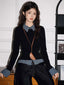 Model wearing a black long-sleeved top with a checkered collar and cuffs, paired with dark wash wide-leg jeans and a brown crossbody bag.