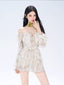 Woman wearing a floral print off-the-shoulder mini dress with bell sleeves and a green floral choker.
