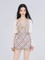 Woman wearing a plaid halter dress with a sheer cropped cardigan