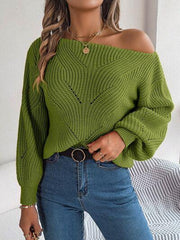 Woman wearing a green off-the-shoulder knit sweater with a textured pattern and lantern sleeves, paired with blue jeans.