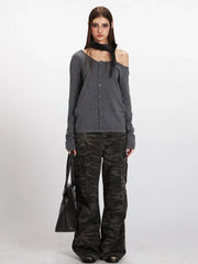 Model wearing a grey off-the-shoulder knit top with camouflage cargo pants and a black handbag.