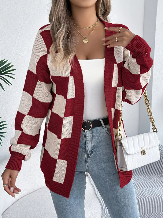Woman wearing a red and cream checkerboard knit cardigan over a white tank top and blue jeans, holding a white quilted handbag.