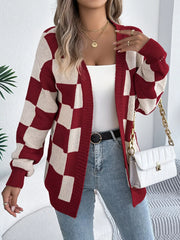 Woman wearing a red and cream checkerboard knit cardigan over a white tank top and blue jeans, holding a white quilted handbag.