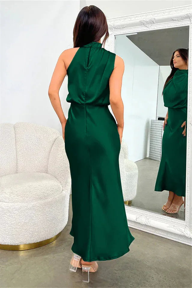 back view of a woman wearing a green satin halter neck midi dress in a dressing room