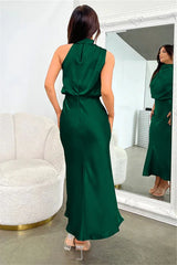 back view of a woman wearing a green satin halter neck midi dress in a dressing room