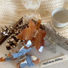 A variety of butterfly hair claw clips scattered on a white knitted fabric