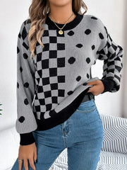 Close-up of a woman wearing a gray and black checkerboard and polka dot knit sweater and blue jeans