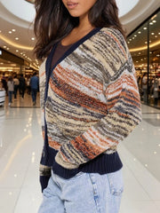Side view of a woman wearing a multicolored striped knit cardigan with a V-neck and button-up front, paired with light-wash jeans.