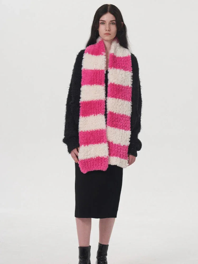 Model wearing a black sweater, black dress, and a pink and white striped fuzzy scarf.