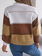 Back view of a woman wearing a brown, tan, and white color block knit sweater with a v-neck and button details, paired with blue jeans.