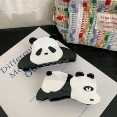 Two panda hair claw clips on a book with a textured bag in the background