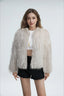 Model wearing a white faux fur jacket with a fringed texture, a cropped length, and an open front, paired with a white crop top and black shorts.