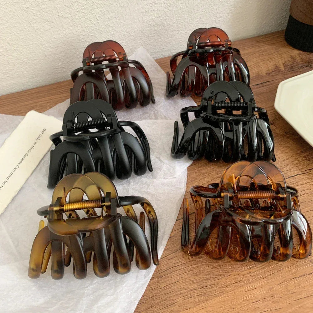 collection of six hair claw clips in black and tortoise shell patterns arranged on a wooden surface