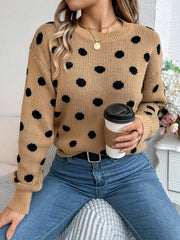 Woman wearing a brown polka dot sweater with blue jeans and holding a coffee cup.